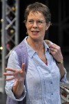 a woman wearing a blouse is standing with her hand outstretched in front of her.