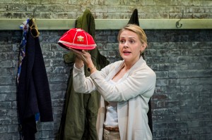 a woman is standing holding up a red hat beside her as though she is presenting it to someone